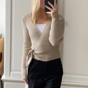 Omlott tröja stickad  - Omlott tröja med knytning. Från Na-kd, använd 2 gånger och är i helt nyskick! Superfin men kommer tyvärr inte till användning längre. 