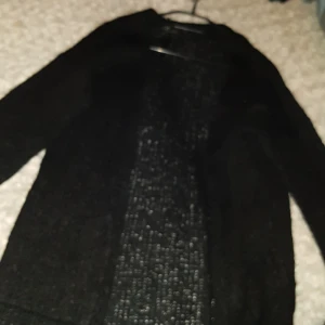 Kofta - Säkjer en mysig svart kofta i stl S. Koftan är öite längre och har fickor på bägge sidor fram. Köparen står för frakten 