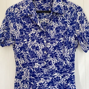 Blommig klänning - Fin klänning med blå blommönster. Kedja på sidan och passar perfekt med ett par höga stövlar eller boots nu till hösten.