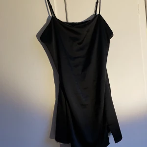 Svart satinklänning - Supersnygg med justerbara axelband och dragkedja i ryggen. Supersnygg och formgivande min lite för tight runt bysten om man som jag har väldigt stor byst. Superbra skick bortsett från att det saknas en liten krok i nacken! Hör av dig om du undrar något!<3