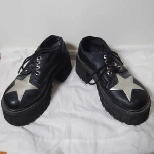 Platåskor - Svarta platåskor med stjärnor. Det finns lite slitningar, syns bäst på sista bilden, men överlag hela och fina. Ingen storleksmärkning men passar  36-37🌱