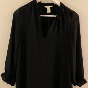 Svart klänning strl S - Svart superfin klänning som sträcker säg till halva armen. Använd 2 gånger. På mig som är ca 175 cm är den ungefär till mitten av låren. Har detaljer vid hals och armar.