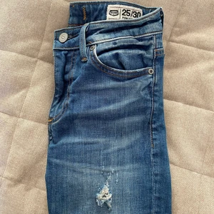 Jeans - Högmidjade Stuprörs jeans med ett hål i ena knät. Strl 25/30