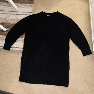 Barbour lång tröja dam stl. 38 - En lite längre svart stickad/virkad tröja från märket Barbour med en guldig dragkedja som detalj vid ena axeln.  Stl. 38  Kan mötas upp i Stockholm men även skicka den, du står dock för frakt. 
