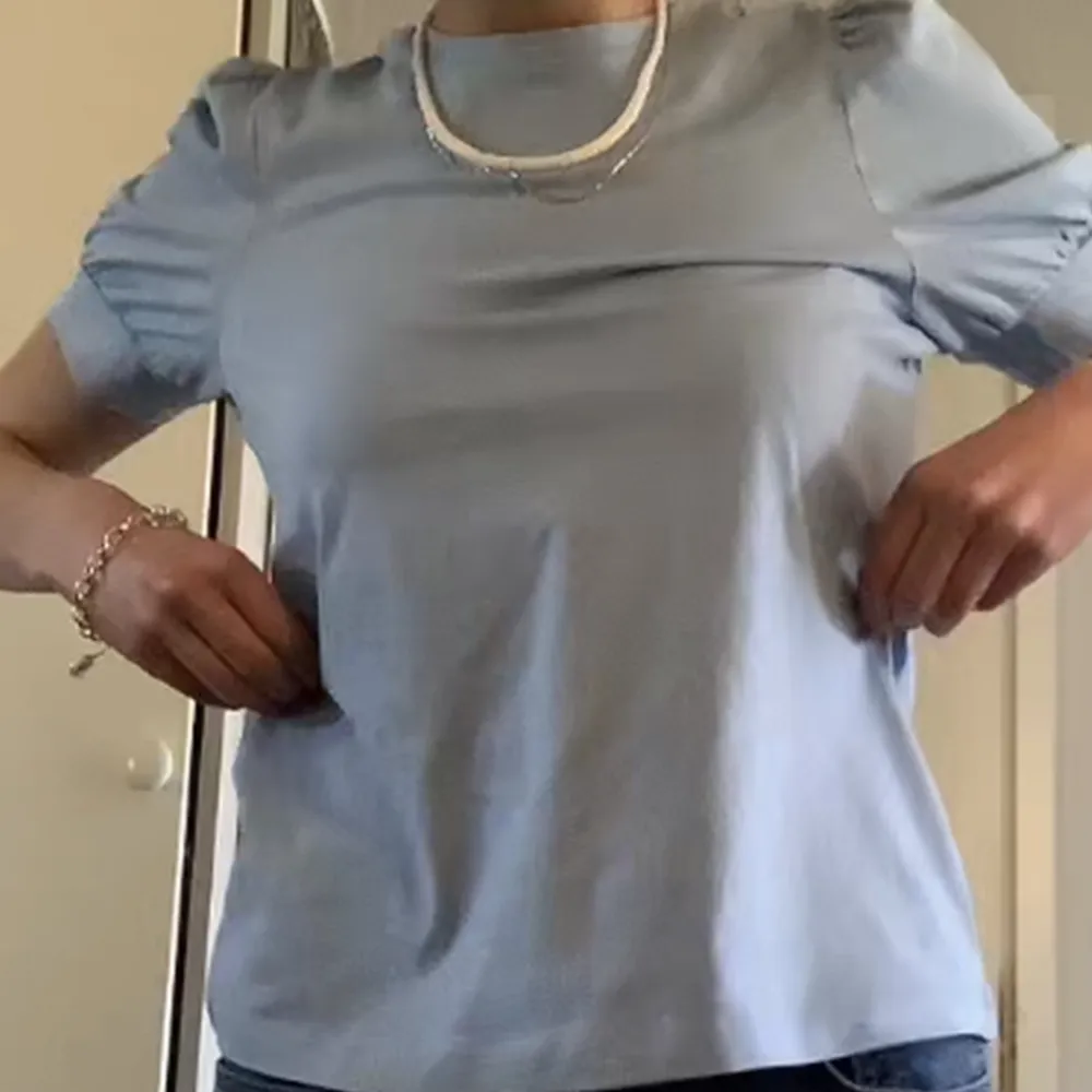 Säljer denna fina t-shirt med söta puffärmar. Obs den är mer blå i verkligheten (syns inte tydligt på bilderna). Är använd fåtal gånger och är i gott skick! . T-paidat.