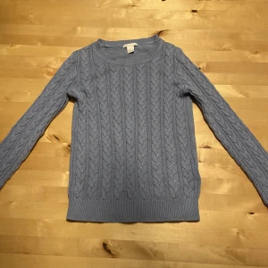 Stickad tröja  - En vanlig stickad tröja med mönster i färgen blå