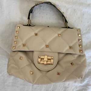 Väska - En beige väska med guldiga nitar, köpt i en random väskaffär utomlands. Valentino-Inspirerad och i ganska ”billigt” material framförallt inuti (se bild 3). Dock fortfarande väldigt fin och enbart använd en gång💘 
