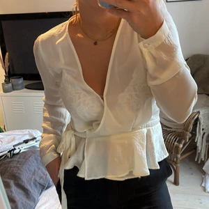 Blus från Nelly - Omlott blus från Nelly i glansigt vitt/benvitt tyg🤍 Storlek 36.
