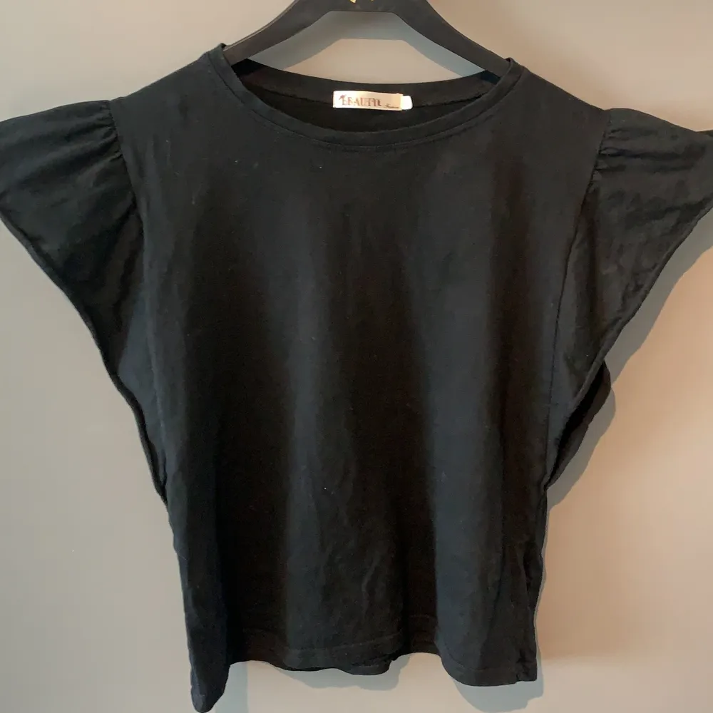 En svart t-shirt/ top med puffiga ärmar (nästan volangaktiga) . T-shirts.