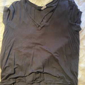 Svart T-shirt med detaljer framtill - Svart T-shirt i mjukt material med detaljer framtill som är sparsamt använd