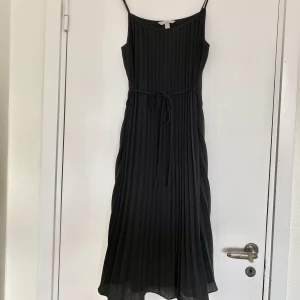 Plisserad klänning strl M - Svart, plisserad klänning i strl M. Använd en gång.