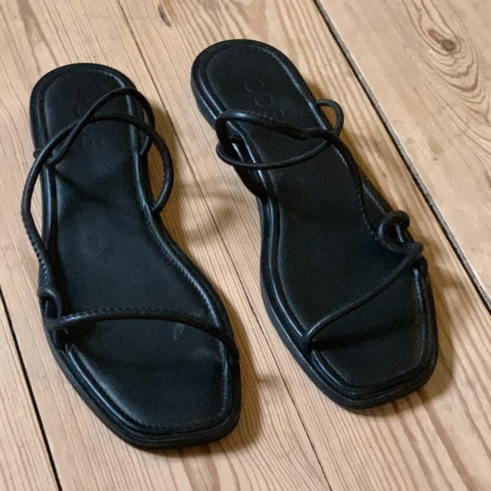 Svarta cleana sandaler i läder från COS. Aldrig använda utomhus. Nån gång inomhus. Bandet som går runt hälen är elastiskt. Som nya.  Eventuell slitning beror på att de köptes på rea och har blivit prövade i butik. . Skor.