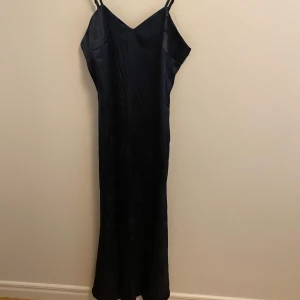 blå satinklänning - En blå satinklänning med blommigt mönster på. Klänningen är ner till fötterna och funkar perfekt till fest.