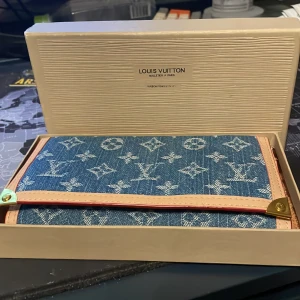 LV plånbok - Gammal men äkta LV jeans plånbok. Knappen som håller fast locket har gått sönder men använd sparsamt ändå. Har allting original förutom kvitto därav priset. 