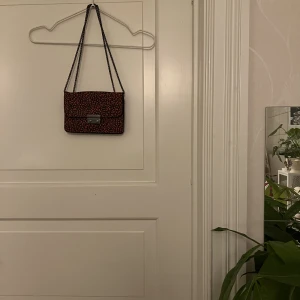 Liten väska🤍 - Liten röd/svart väska. 20cmX15cm. Går att ha över axeln och crossbody. Liten repa (se bild) men inget som syns när väskan är stängd. Använd ett fåtal gånger. Kan mötas i Göteborg eller skicka, köparen står för frakt.