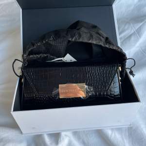 Säljer en helt ny svart axelremsväska från ideal of sweden i modellen ”black rocco bag”. Nypris är 899kr. Den är helt ny, aldrig använd, förplackning, låda och påse finns kvar och medkommer. ❤️Axelrems bandet medkommer och har nitar i form av prickar på.