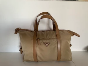 Beige Prada bag - INKLUSIVE FRAKT❣️📦 Beige 2000s Prada bag. Perfekt väska för skola eller jobb.  ❣️Skicka PM Vid frågor eller om fler bilder önskas!!  Finns små fläckar på väskan men inget klart synligt. 