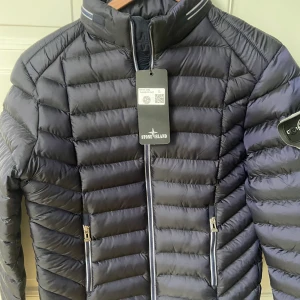 Interjacka - Stone Island inspirerad vinterjacka. Storlek L men mer som M i storleken. Längd ca 65 cm. Mörkblå.