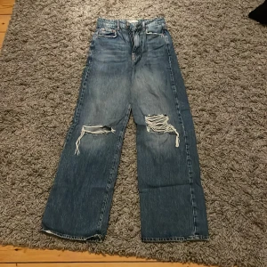 Vida jeans str 34 - Jeans från Gina, slitna knän och vida nertill. Inte så jätte använda. Tillkommer frakt eller möta upp i O-hamn.