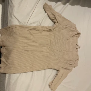 Kortärmad tröja  - Kortärmad tröja v-ringad som inte ligger i mitten.  Tröjan är beige och i storleken xs 