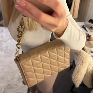 Beach zara väska - Jättesnygg beige väska från zara med guldig axelkedja💕 Säljer då den ej kommer till användning. Aldrig använd.