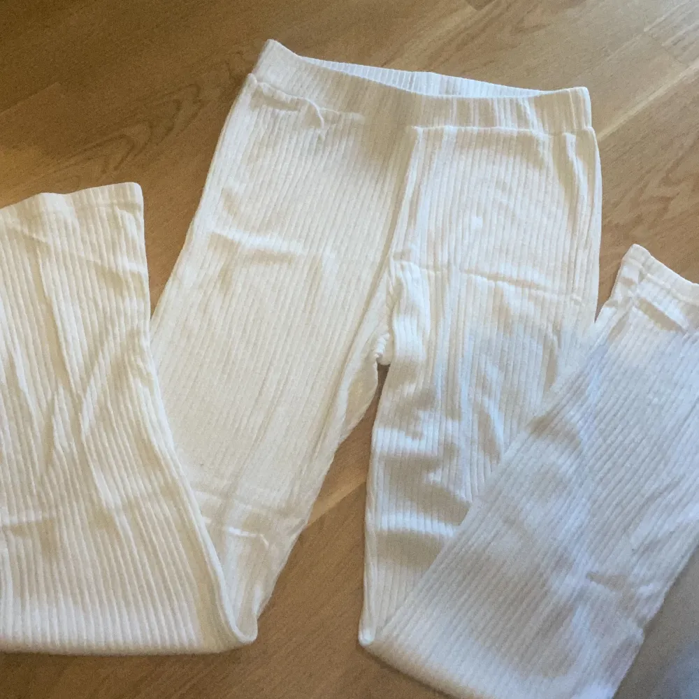 Ett par vita ribbstickade byxor med lite  bootcut från ginatricot i st M. Dom är i bra skick och använda få gånger. Nypris 250kr. Jeans & Byxor.