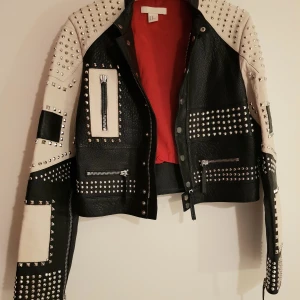 Läcker svartvit läderjacka med nitdetaljer - Jacka i äkta läder med svart o vit mönster o nit detaljer. Nypris 2999. I mycket gott skick.
