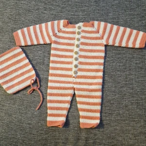 Baby overall - Denna fina overall har jag virkat. En mössa tillkommer. Garnet är av bomull. Tvättas i 30 grader. Knapparna är av plast.  Passar nyfödda barn.  Finns i rök och djurfritt hem. Köparen står för frakten