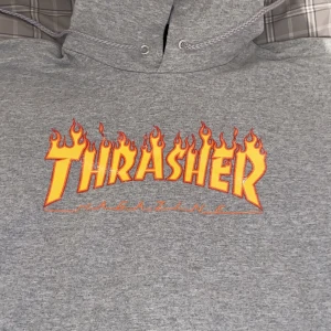 Thrasher hoodie - En thrasher hoodie som numera ligger kvar i garderoben och inte får mycket användning, köpt för ungefär 2-3 år sen från Junkyard. Är själv 170cm och den passar perfekt på mig. Original pris 1000kr. Skick 6/10 - se bilder, största märkbara finns vid loggan