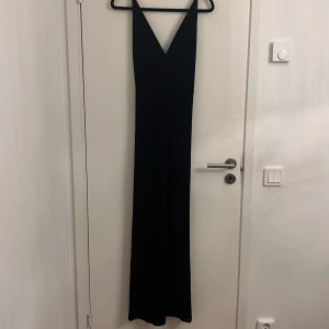 Klänning  - Svart lång klänning med fina detaljer på ryggen. Köpt från bikbok för cirka 800kr. Ej använd.