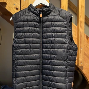 Save the duck väst  - Save the duck väst. Superfint skick, sparsamt använd under 1 säsong tillvardags samt under golfspel. Storlek L använts av kille på 180cm