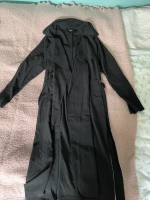 Kappa - Lång tunn svart kappa med band som kan knytas eller tas bort helt. Går nedanför knäna. I fint skick!