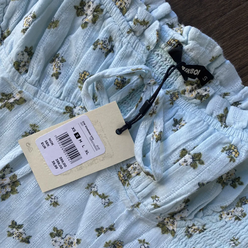 En kort blå blommig klänning från BikBok, storlek S. Aldrig använd så prislappen är kvar! Stretchig i materialet bak. ❤️. Klänningar.