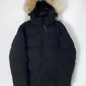 Canada Goose - Canada Goose jacka av äldre modell (Vet ej modellnamn). Jackan är storlek M och håller värmen även under de kyligaste dagarna på året. Längden på jackan är av de längre men endast lite över midjan, alltså inte ända ner till knäna. 