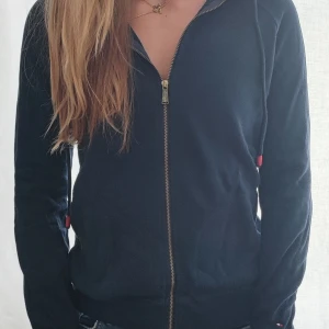 Tommy Hilfiger Zip hoodie. - Fin hoodie med tryck på ryggen. Randig i luvan. Passar XS-S
