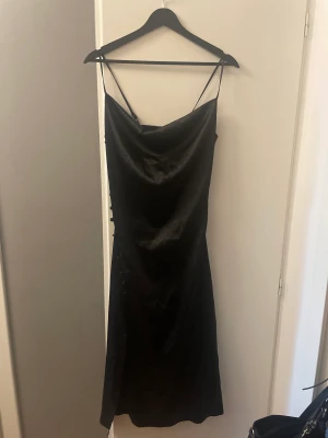 Klänning - Svart satin klänning, minns ej vart den är köpt. Väldigt fin men kommer ej till användning. Slits på sidan med knappar upp. 