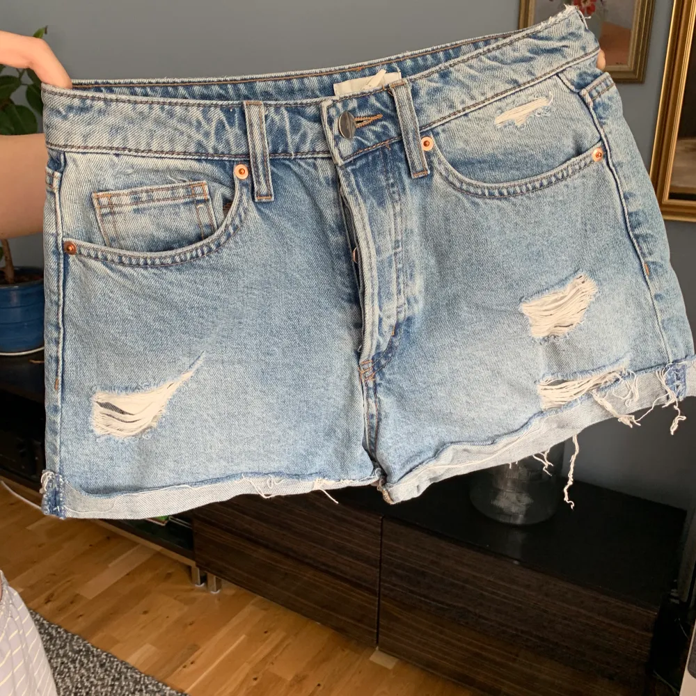 Jeansshorts med slitningar från H&M, strlk 36. På mig som har mellan strlk 36-38 sitter de högmidjat och tajt. Allmänt fint skick, men köpta på stadsmissionen.. Shorts.