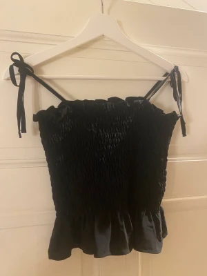 Gullig topp - Svart topp som är perfekt till både vardag och fest. Sparsamt använt med justerbara band. 