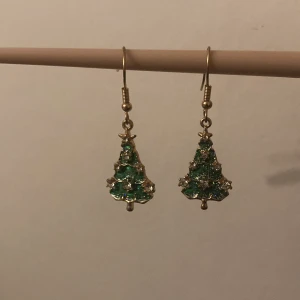 Julgrans örhängen  - Dom här örhängen har bara använts 1 gång och är i väldigt fint skick.  Dom är gröna på framsidan med lite glitter och sedan är dom guldiga på baksidan. 