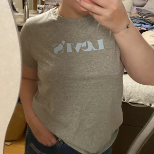 Grå T-shirt från Levis  - En fin grå Levis t-shirt med blått tryck, andvänd ca 2 ggr i strl M/L 