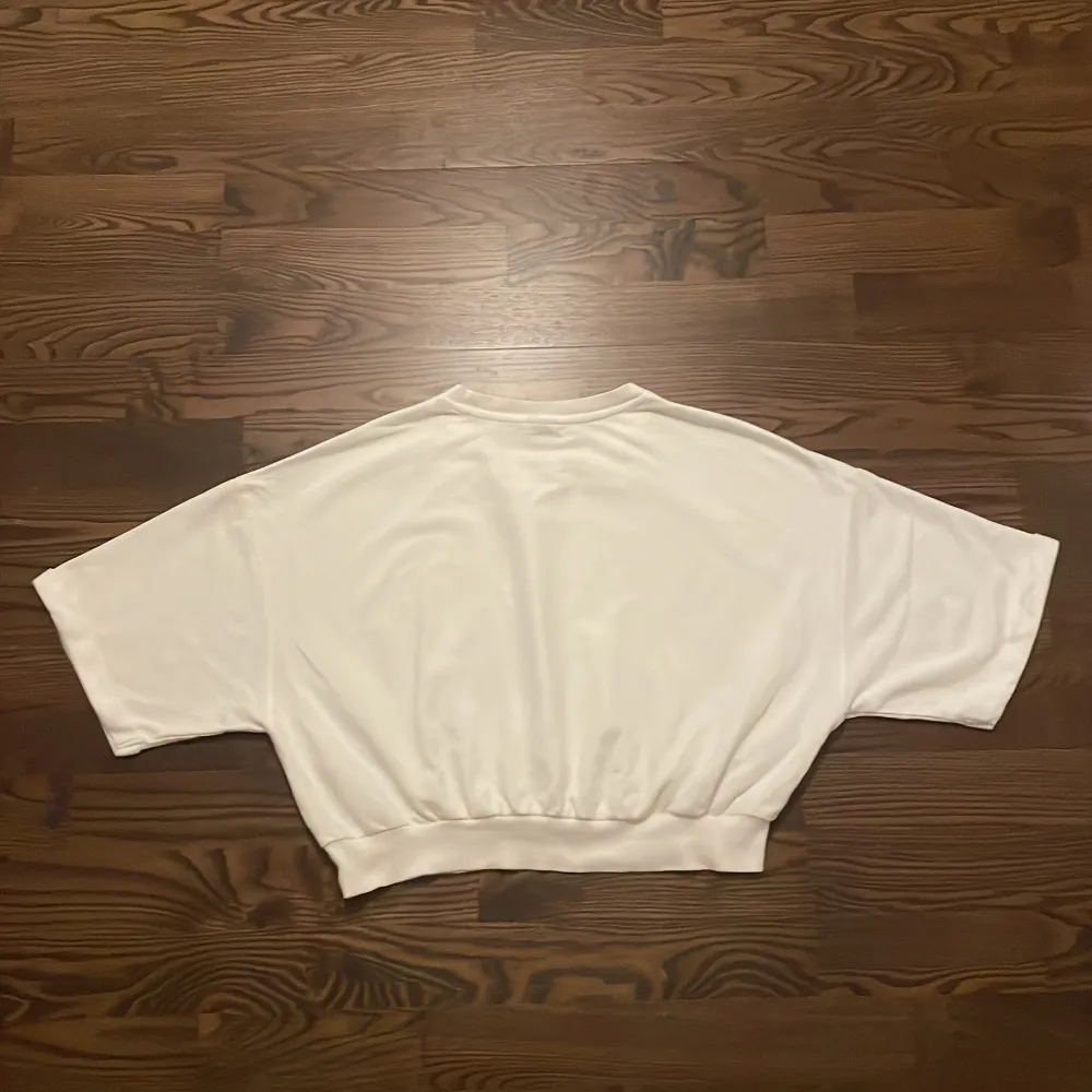 Kort vit T-shirt från Gina Tricot. Bra skick. Trekvartsärm och kort vid magen. . T-shirts.