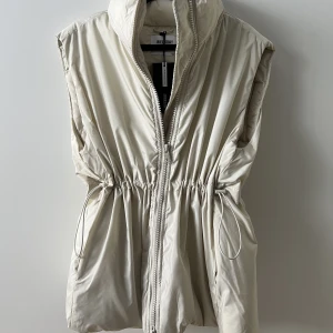 Väst - Helt ny väst från weekday. Mjölkvit färg. Tjock och luftig, jättemjuk och skön! Har dragsko runt midjan så man kan dra in det. 