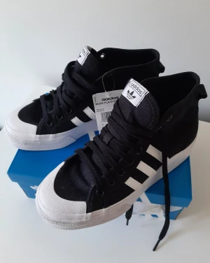 Platå sneakers - adidas Nizza Platform MD - Oanvända snygga höga sneakers från adidas Orginals. Upptäckte försent att de var lite för små för mig o kunde inte längre byta strl i butik. Jag pendlar mellan 39 & 39 1/5. Hade behövt 39 1/5 i dessa. Har kostat 999kr. Kommer i tillhörande skokartong.