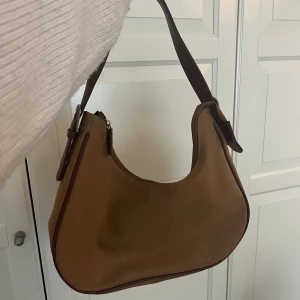 Brun väska ”mocka” - Super fin väska i mocka imitation. Köpt här på plick. Lite sliten men inget är sönder. Väldigt rymlig,