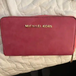 Snygg större rosa plånbok från Michael Kors. Sparsamt använd så i fint begagnat skick.  Längd ca 20cm. Bredd ca 10cm.