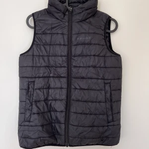 Dunväst  - En svart Everest väst i barn storlek. Har lite smink runt kragen. 