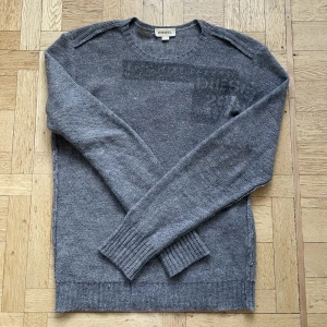 Grå stickad Diesel Tröja med tryck L - Grå stickad tröja från Diesel med stickat tryck i en blandning av Ull och Alpaca Ull. I storlek XL men passar som L. I mycket fint skick!