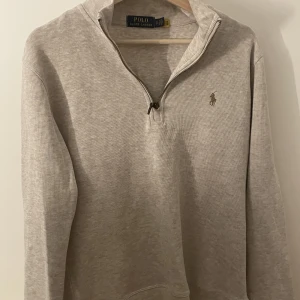 Ralph Lauren 1/4 zip - Stickad Ralph Lauren zip i nyskick då den bara använts ett fåtal gånger, perfekt under en jacka nu till höst/vinter men även bra för dem kyligare sommarkvällarna