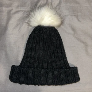 Mössa - Svart mössa med en vit boll.