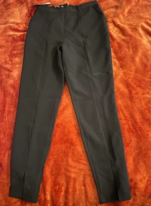 Figursydda Ankel kostymbyxor med slits - Slits på framsidan och dragkedja på baksidan. Oanvänd med prislapp på!